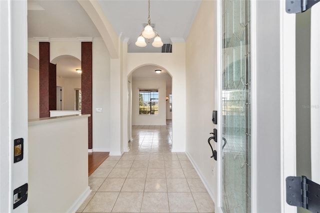 tiled entrance foyer with a chandelier and crown molding