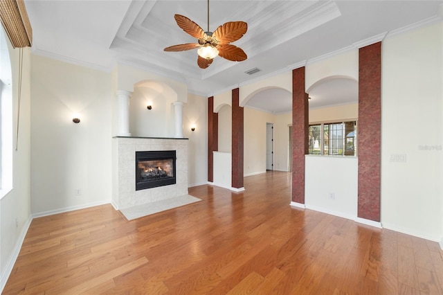 unfurnished living room featuring light wood-type flooring, a raised ceiling, ceiling fan, and crown molding