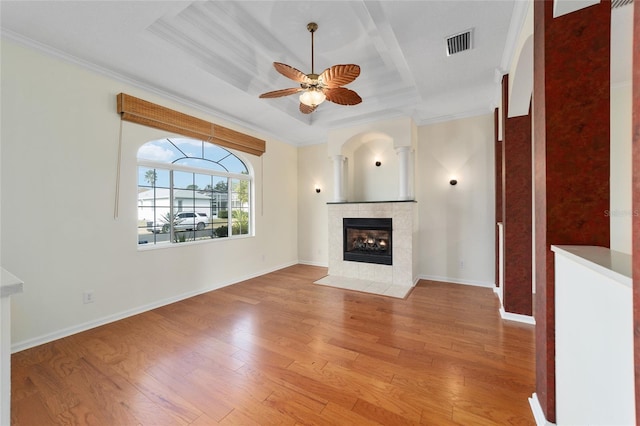 unfurnished living room with a raised ceiling, ceiling fan, crown molding, and light wood-type flooring