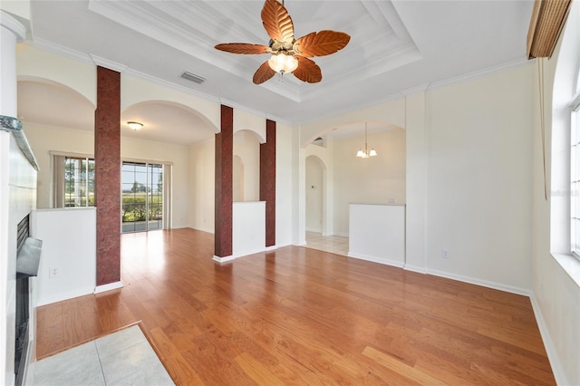 unfurnished room featuring ceiling fan with notable chandelier, a tray ceiling, light hardwood / wood-style flooring, and crown molding