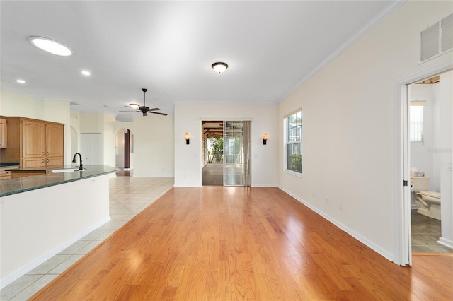 unfurnished living room with ceiling fan, crown molding, sink, and light hardwood / wood-style flooring