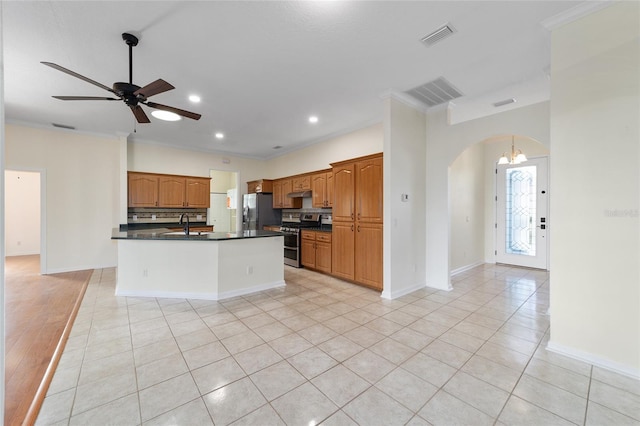 kitchen featuring crown molding, a kitchen island with sink, light tile patterned flooring, ceiling fan with notable chandelier, and appliances with stainless steel finishes