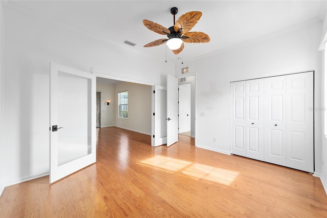 unfurnished bedroom featuring ceiling fan, a closet, crown molding, and light hardwood / wood-style flooring