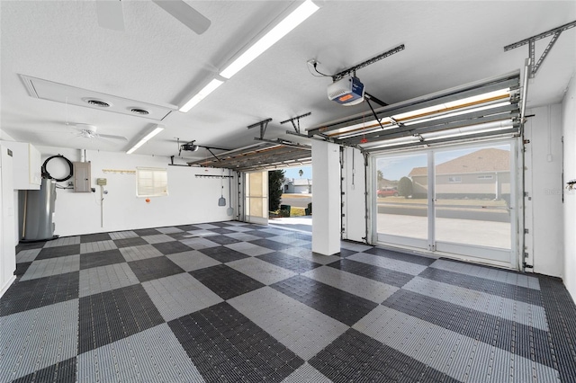 garage with electric panel, a garage door opener, ceiling fan, and water heater