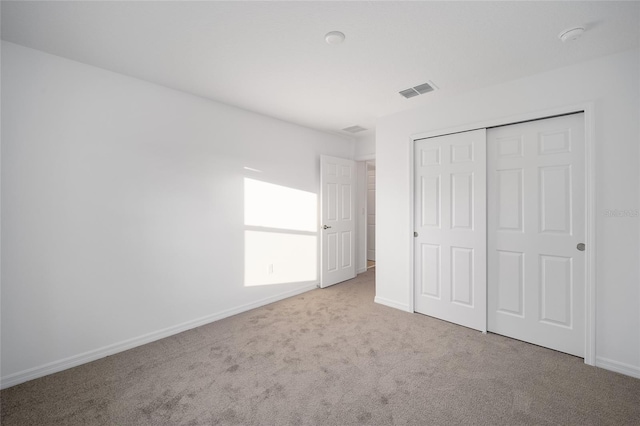 unfurnished bedroom with light carpet and a closet