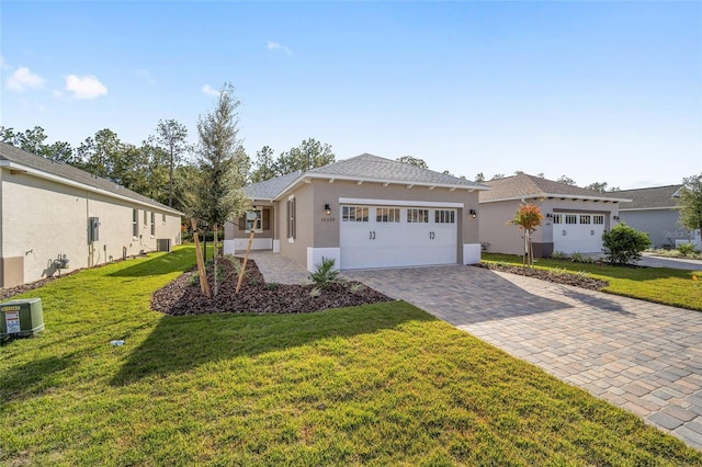 single story home featuring a garage, a front lawn, and central air condition unit