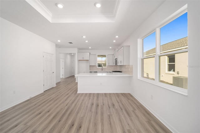 kitchen featuring kitchen peninsula, white cabinetry, crown molding, and light hardwood / wood-style floors