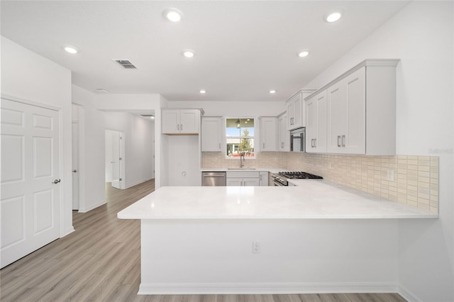 kitchen featuring kitchen peninsula, light hardwood / wood-style flooring, stainless steel appliances, and sink