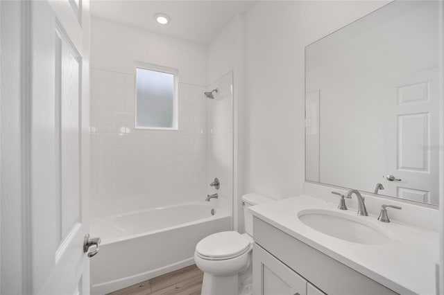 full bathroom with hardwood / wood-style floors, tiled shower / bath combo, toilet, and vanity