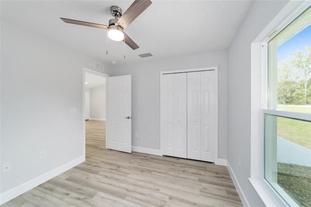 unfurnished bedroom featuring ceiling fan, a closet, and light wood-type flooring