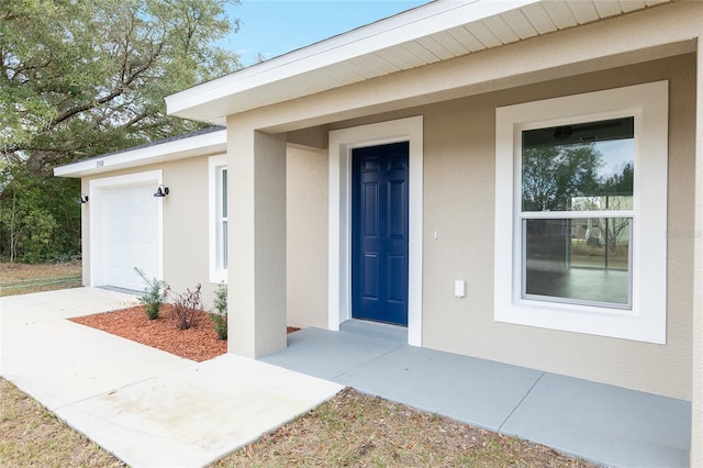 doorway to property featuring an attached garage and stucco siding