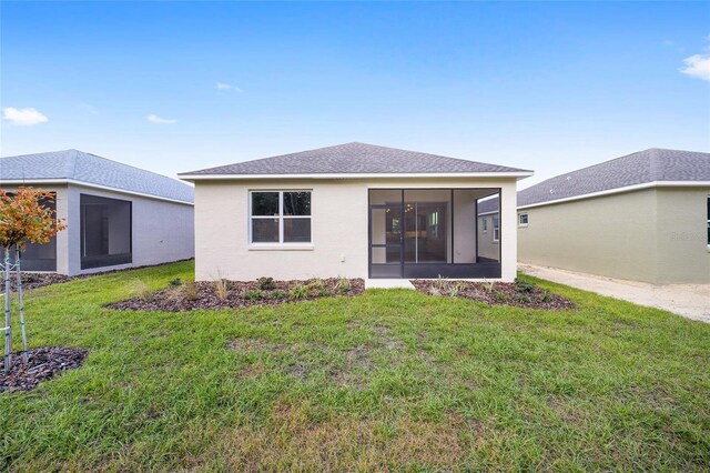 rear view of house featuring a sunroom and a lawn