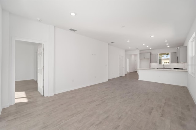 unfurnished living room featuring light hardwood / wood-style flooring and sink