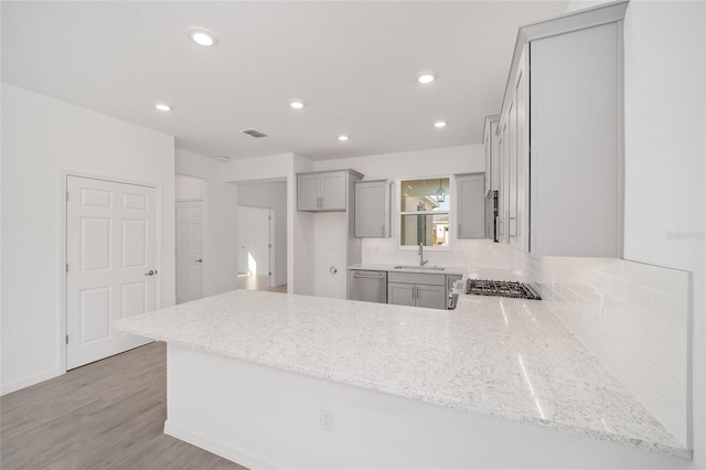 kitchen with gray cabinetry, sink, stainless steel appliances, light hardwood / wood-style flooring, and kitchen peninsula