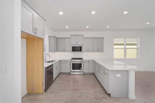 kitchen with gray cabinets, kitchen peninsula, sink, and appliances with stainless steel finishes