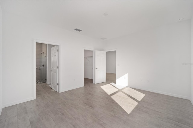 unfurnished bedroom featuring a closet, a spacious closet, and light hardwood / wood-style flooring