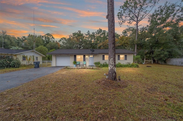 ranch-style house with a garage and a lawn