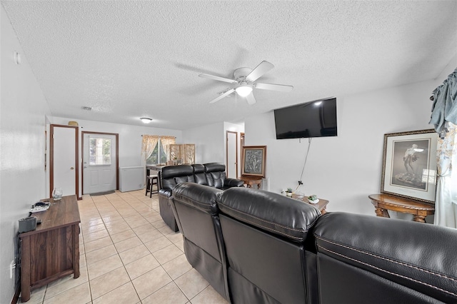 living room featuring ceiling fan, light tile patterned flooring, and a textured ceiling