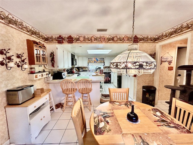 dining space featuring light tile patterned floors and a skylight