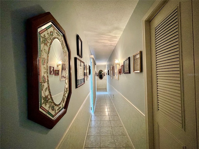 hall featuring light tile patterned floors and a textured ceiling