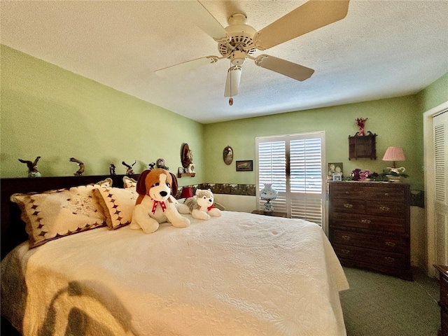 bedroom with ceiling fan, carpet floors, and a textured ceiling