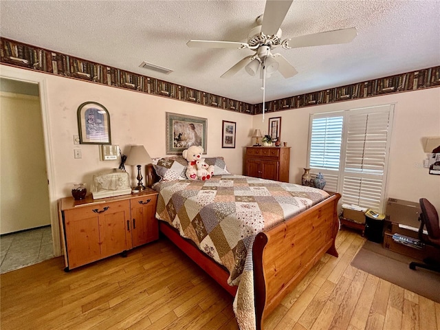 bedroom featuring ceiling fan, light hardwood / wood-style flooring, and a textured ceiling