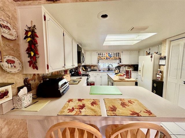 kitchen with white appliances, sink, white cabinetry, light tile patterned flooring, and kitchen peninsula