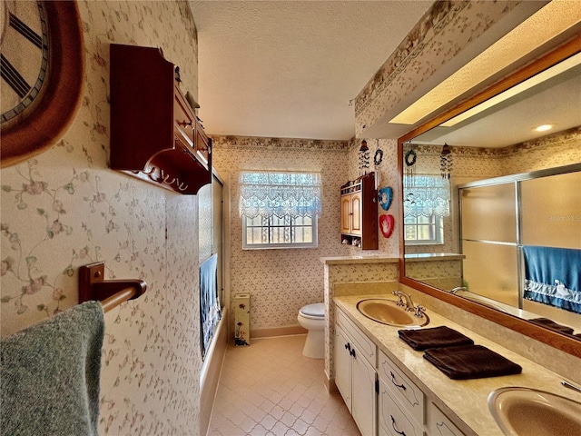 bathroom featuring a textured ceiling, vanity, a shower with door, tile patterned flooring, and toilet