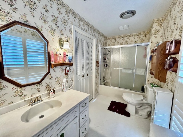 full bathroom featuring shower / bath combination with glass door, a textured ceiling, vanity, and toilet