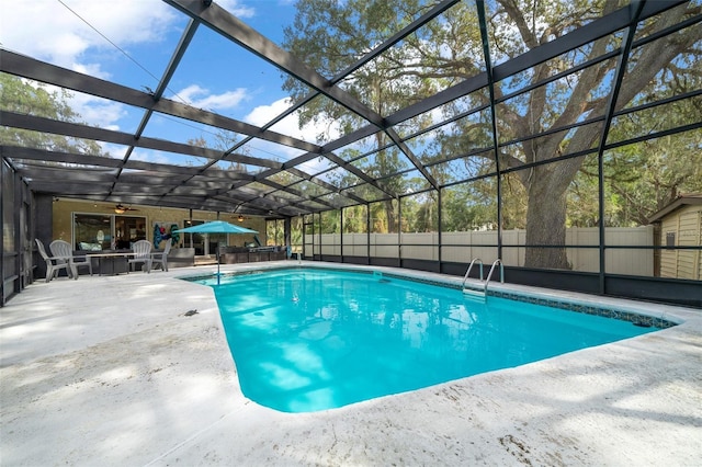 view of pool featuring glass enclosure, ceiling fan, and a patio area