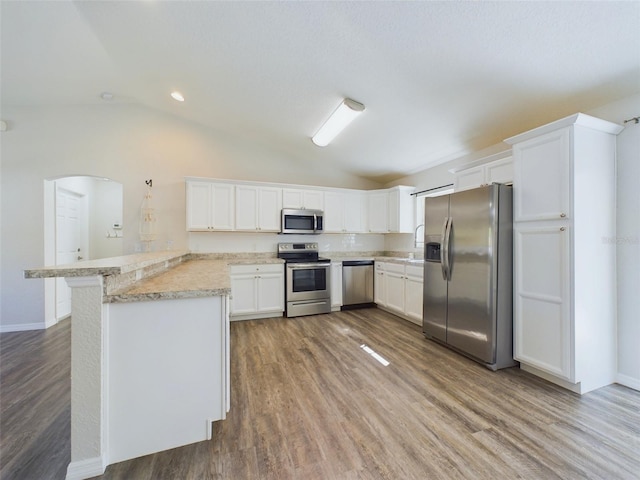 kitchen featuring lofted ceiling, white cabinets, hardwood / wood-style flooring, appliances with stainless steel finishes, and kitchen peninsula