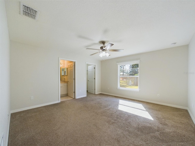 unfurnished bedroom featuring a textured ceiling, carpet floors, ensuite bathroom, and ceiling fan