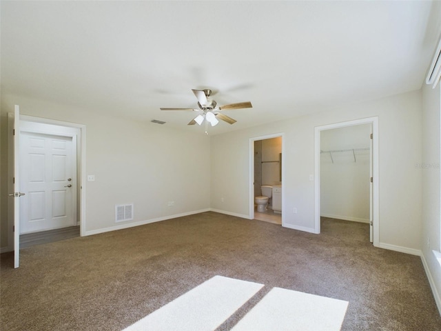 unfurnished bedroom featuring connected bathroom, ceiling fan, a spacious closet, a closet, and carpet