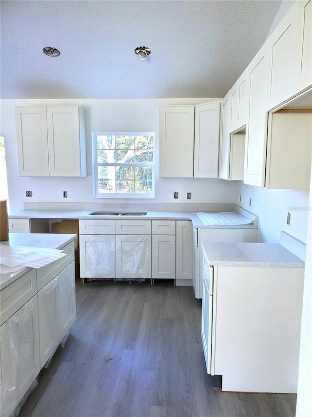 kitchen featuring a textured ceiling, sink, white cabinets, and dark hardwood / wood-style floors