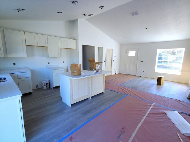 kitchen featuring white cabinets, a kitchen island, wood-type flooring, and high vaulted ceiling