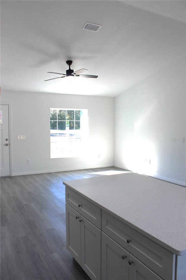 empty room with a textured ceiling, dark wood-type flooring, and ceiling fan