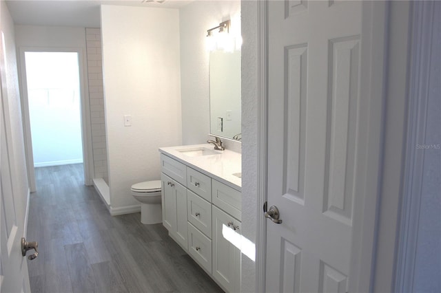 bathroom with walk in shower, vanity, toilet, and hardwood / wood-style floors