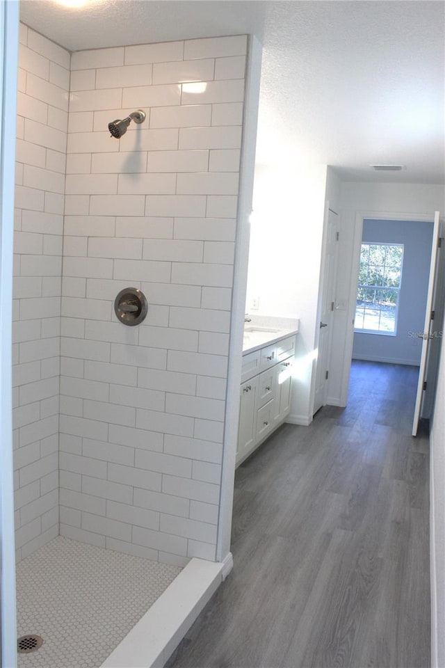 bathroom featuring hardwood / wood-style flooring, vanity, and a tile shower