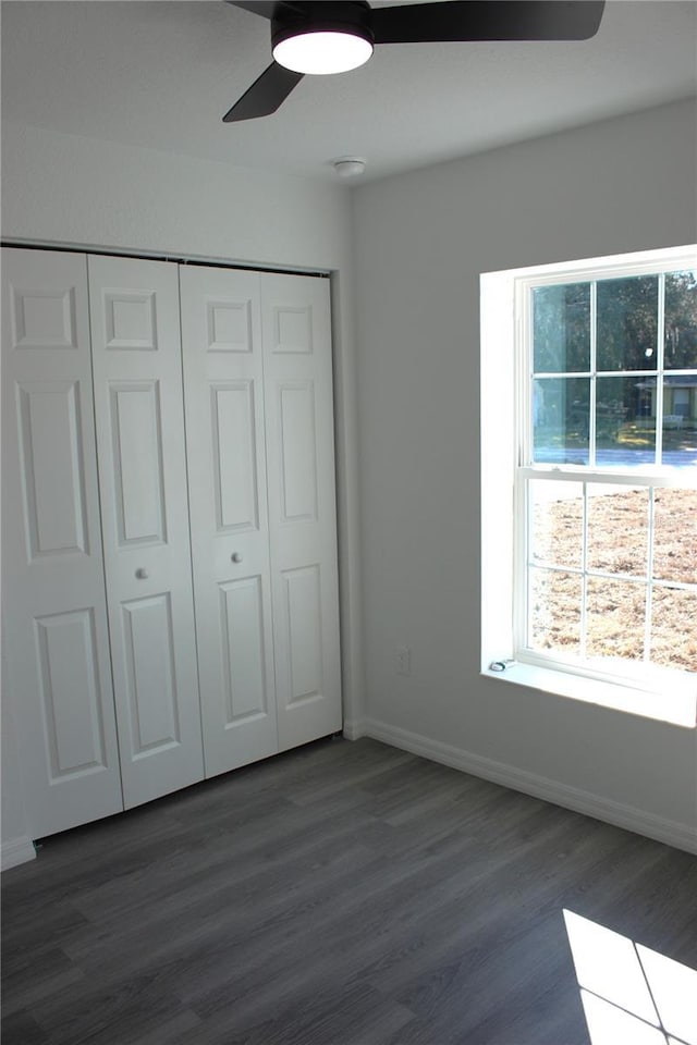 unfurnished bedroom featuring dark wood-type flooring, a closet, and ceiling fan