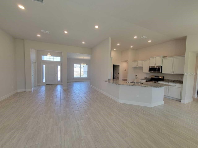 kitchen with light stone countertops, sink, stainless steel appliances, and white cabinetry