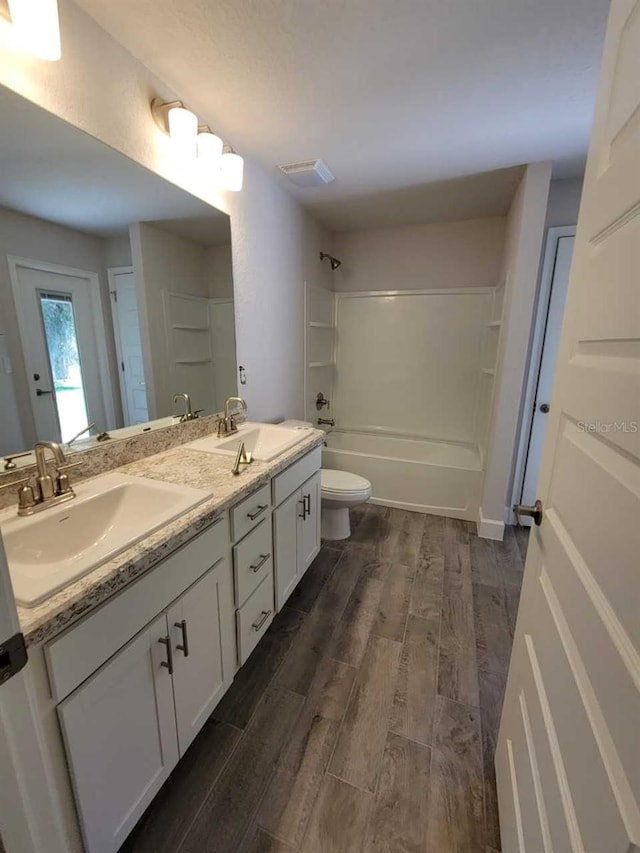 full bathroom with hardwood / wood-style flooring, shower / bath combination, toilet, and vanity