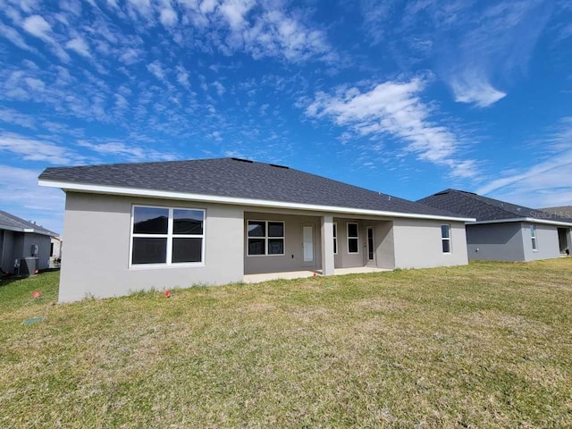 rear view of house with central air condition unit and a yard