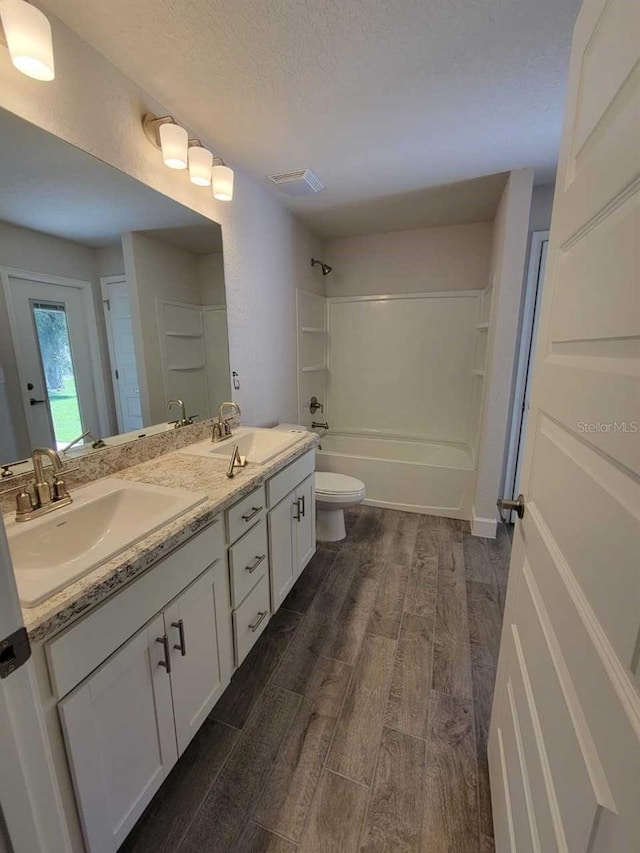 full bathroom with a textured ceiling, toilet, washtub / shower combination, and vanity