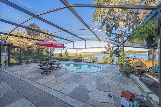 view of swimming pool with glass enclosure, a water view, and a patio