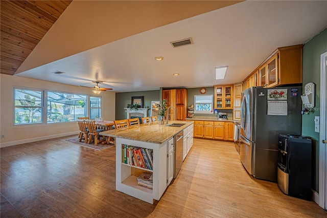 kitchen with sink, stainless steel appliances, light hardwood / wood-style floors, lofted ceiling, and a kitchen island with sink