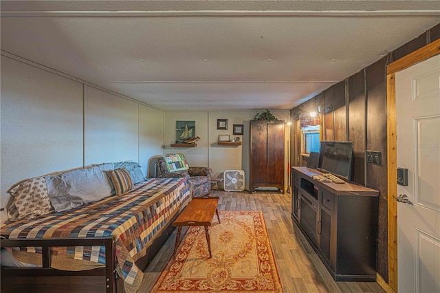 living room featuring wood walls, a textured ceiling, and light hardwood / wood-style flooring