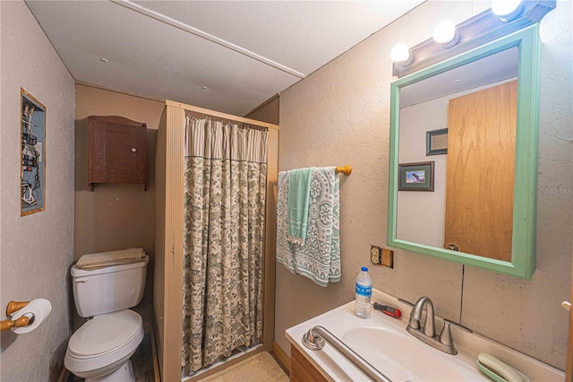 bathroom with a shower with shower curtain, vanity, toilet, and a textured ceiling