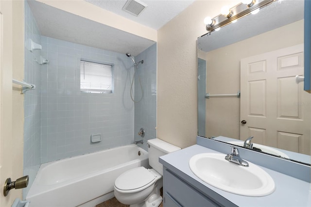 full bathroom featuring toilet, vanity, a textured ceiling, and tiled shower / bath