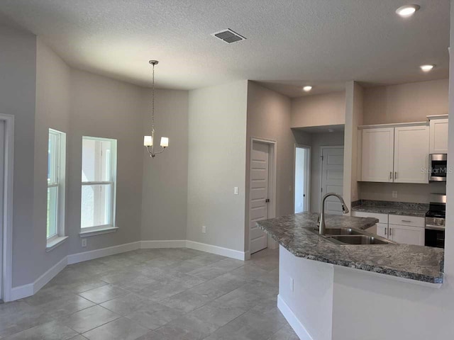 kitchen with stainless steel appliances, a notable chandelier, decorative light fixtures, white cabinets, and sink