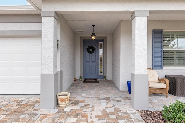 view of exterior entry with a porch and a garage